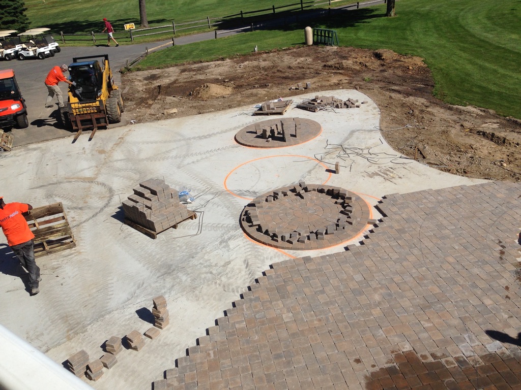 Terranova crew in orange laying the circular paver patterns at Pine Hills in Manorville